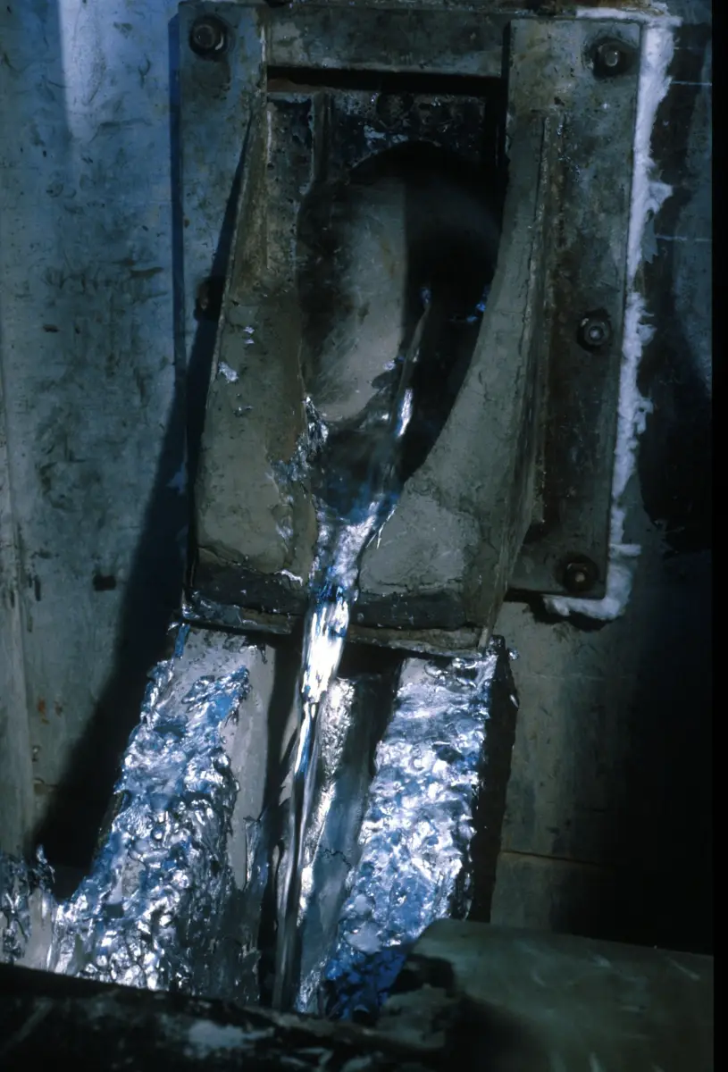 Liquid metal poured into a steel mould, glowing silver and blue